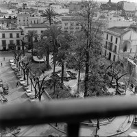 Vista cenital de la Plaza del Duque de la Victoria desde la Casa Sindical. Se aprecia a la derecha el inicio del derribo del palacio de Sánchez-Dalp para la construcción de los grandes almacenes El Corte Inglés. Enfrente, la fachada del tablao El Patio Andaluz junto a una tienda de confecciones y una peluquería. 1965 ca. ©ICAS-SAHP, Fototeca Municipal de Sevilla, fondo Cubiles